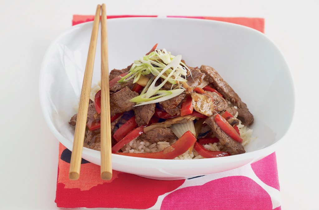 Beef stir-fry with red capsicum strips in a white bowl, served with chopsticks and a bright red marimekko napkin.