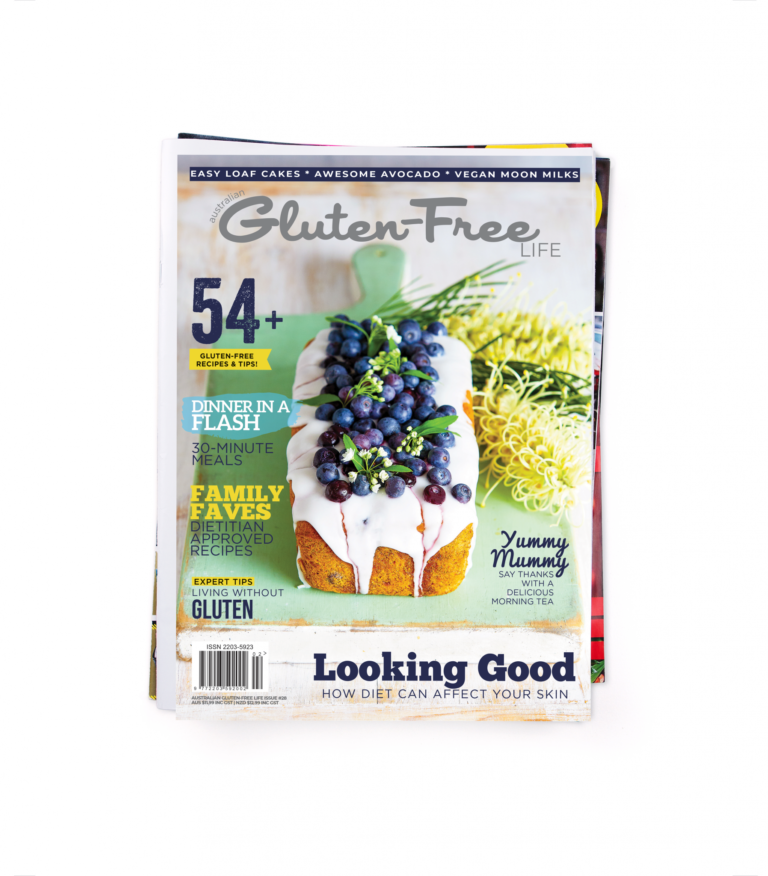 Gluten-Free Magazine with blueberry banana cake sitting on a green board with yellow flowers.