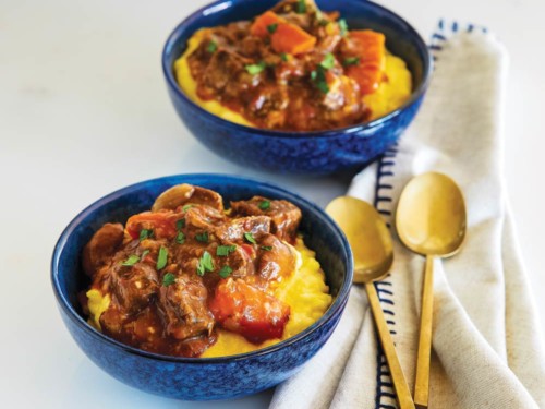 Blue bowls with slow cooker beef stew served on cheesy polenta