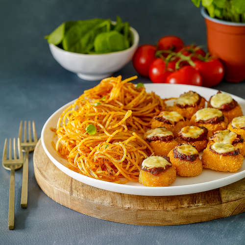 gluten-free chicken nugget parmigiana and gluten-free spaghetti on a white plate sitting on a board.