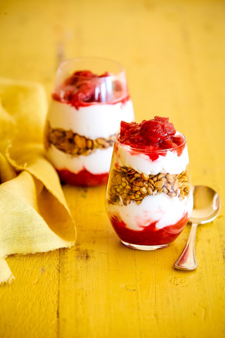 gluten-free breakfast parfait with stewed rhubarb in two glasses on a yellow background