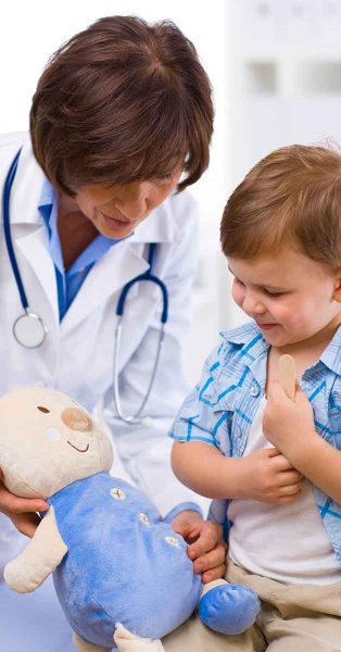 Young boy holding with soft toy talking to a female doctor.