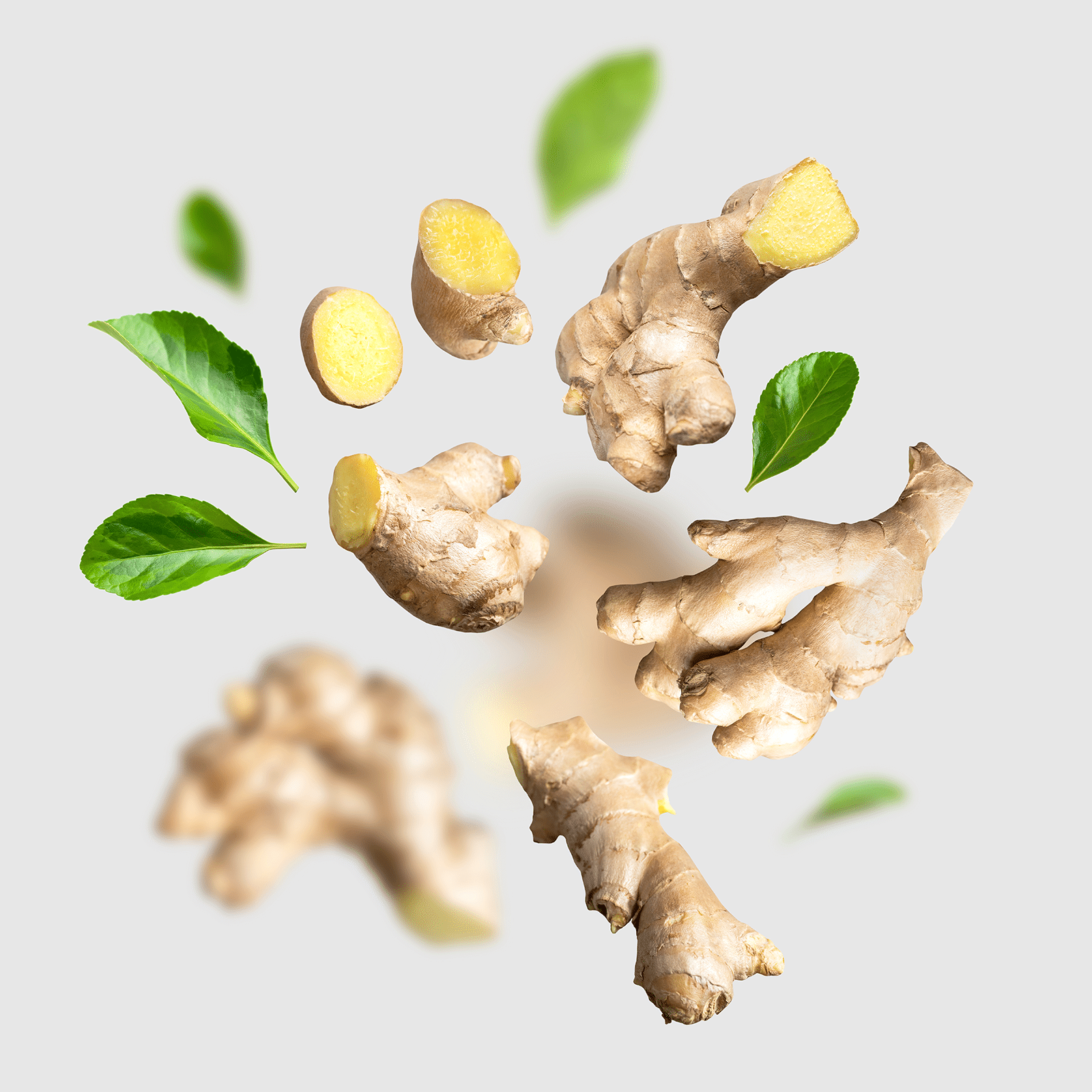 Sliced ginger thrown in air on a grey background.