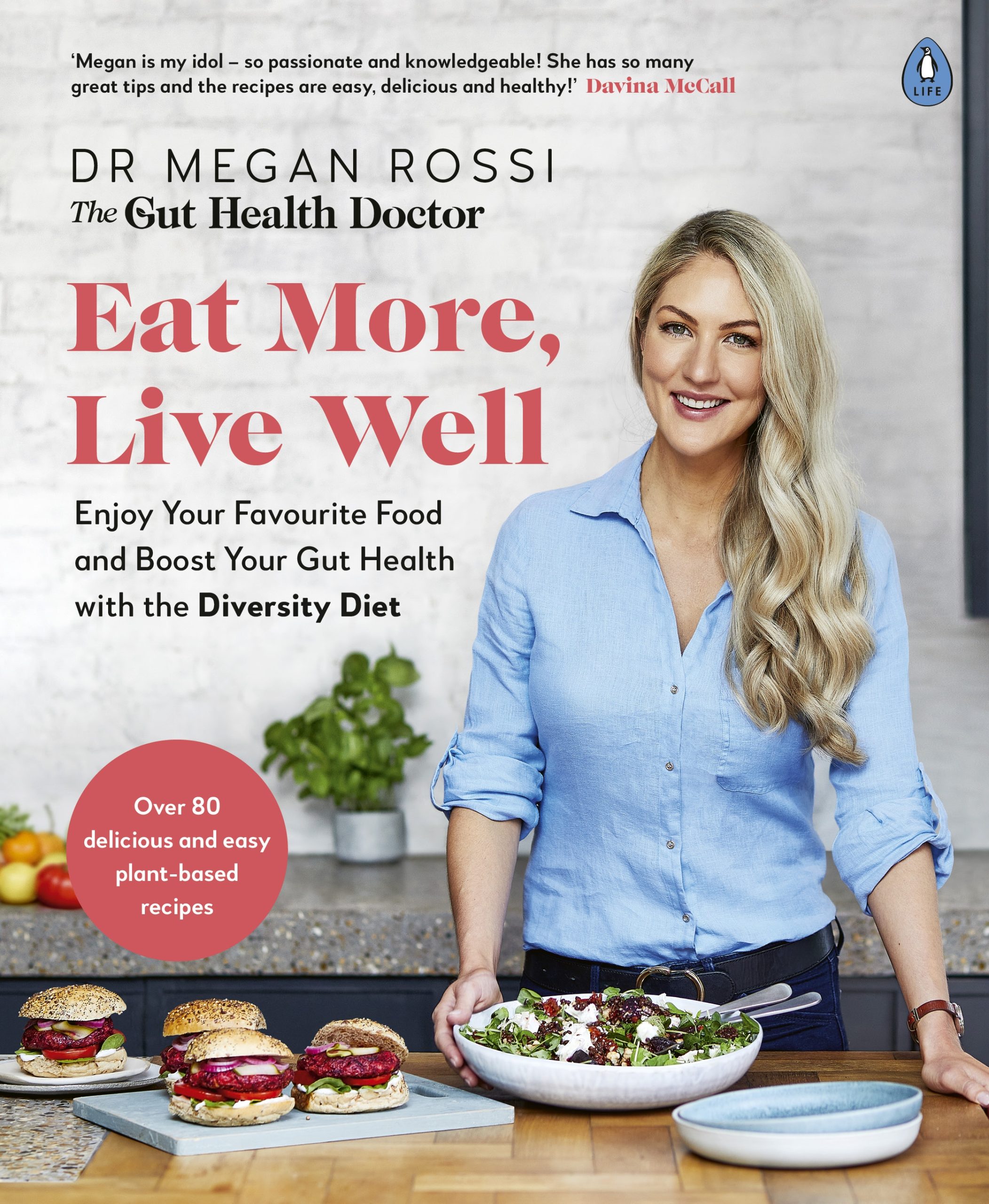 Cover of Eat More, Live Well, by Dr. Megan Rossi. Penguin Life, RRP AUD $35. Featuring Dr Rossi wearing a blue shirt standing in a kitchen with food in front of her.
