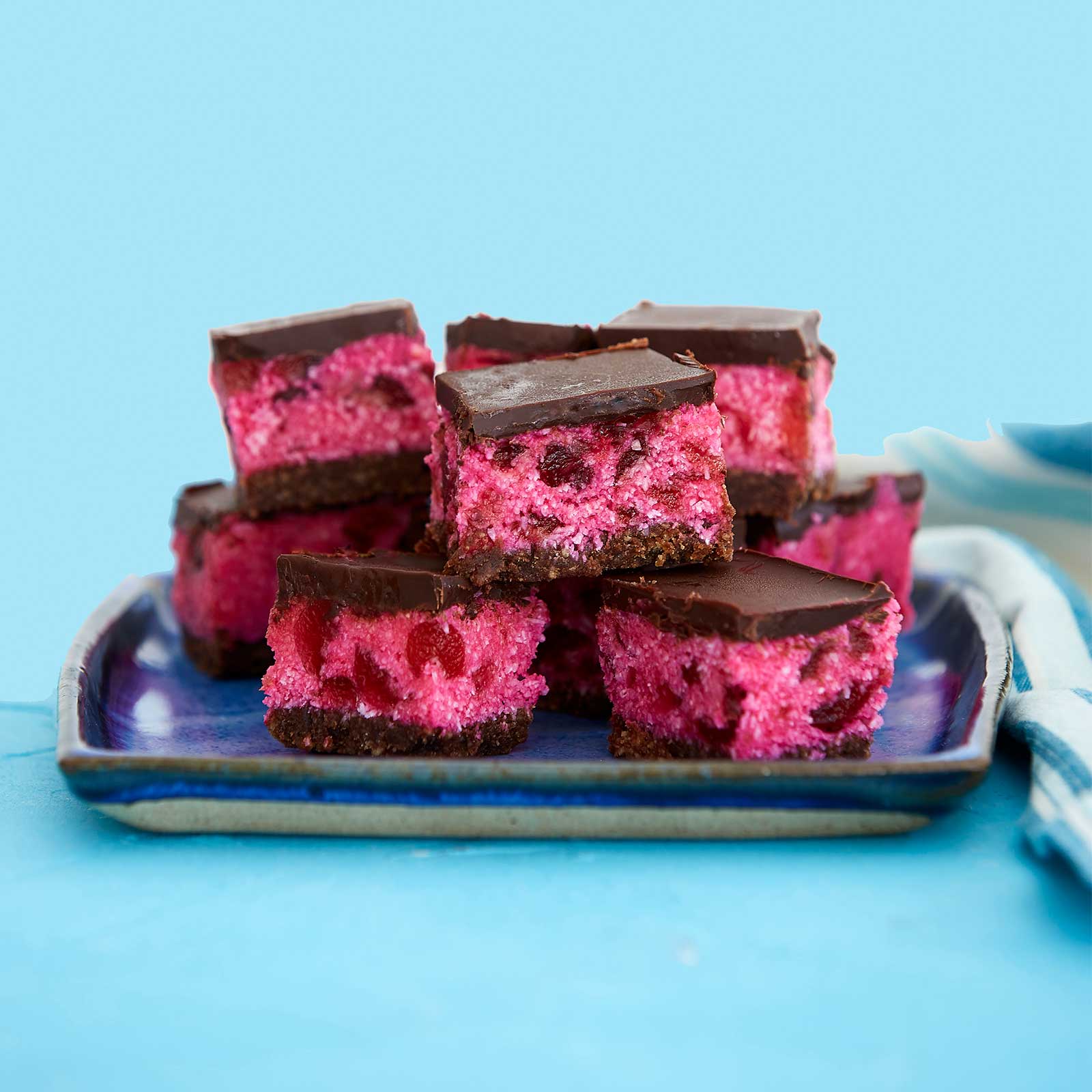 Gluten- and dairy-free cherry ripe slice cut into squared and arranged on a square blue plate.
