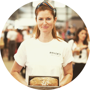 Nonie Dwyer standing at Carriageworks markets hold a loaf of her gluten-free bread.