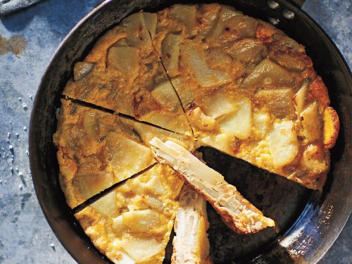 Tortilla De Patatas in a oven-proof pan. Shot overhead and sliced into wedges ready to serve.