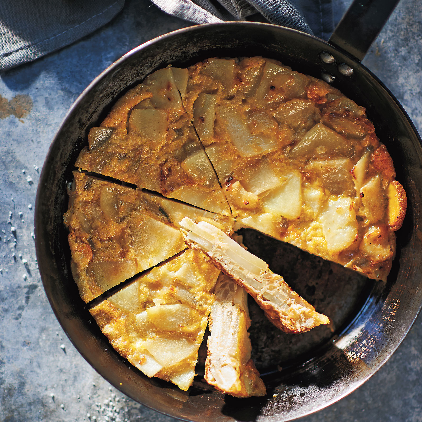Tortilla De Patatas in a oven-proof pan. Shot overhead and sliced into wedges ready to serve.