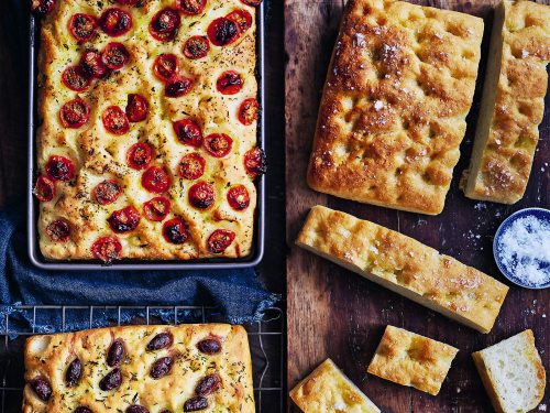 Three different types of gluten-free focaccia (plain, Pugliese and olive & rosemary). Fresh out of the oven. The plain gluten-free foccacia is on a wooden board and has been sliced.