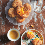 Gluten-free pumpkin cakes are arranged on a dish. The cakes are an Asian dessert and coated in sesame seeds.