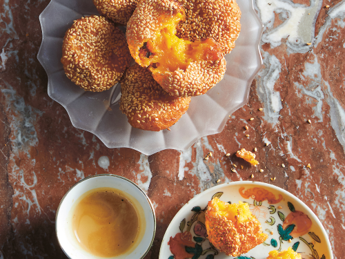 Gluten-free pumpkin cakes are arranged on a dish. The cakes are an Asian dessert and coated in sesame seeds.