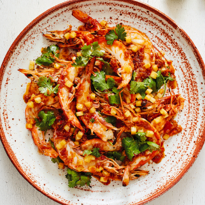 Orange and white ceramic bowl with barbecued prawns (sliced lengthways) topped with gluten-free sambal and diced pineapple.