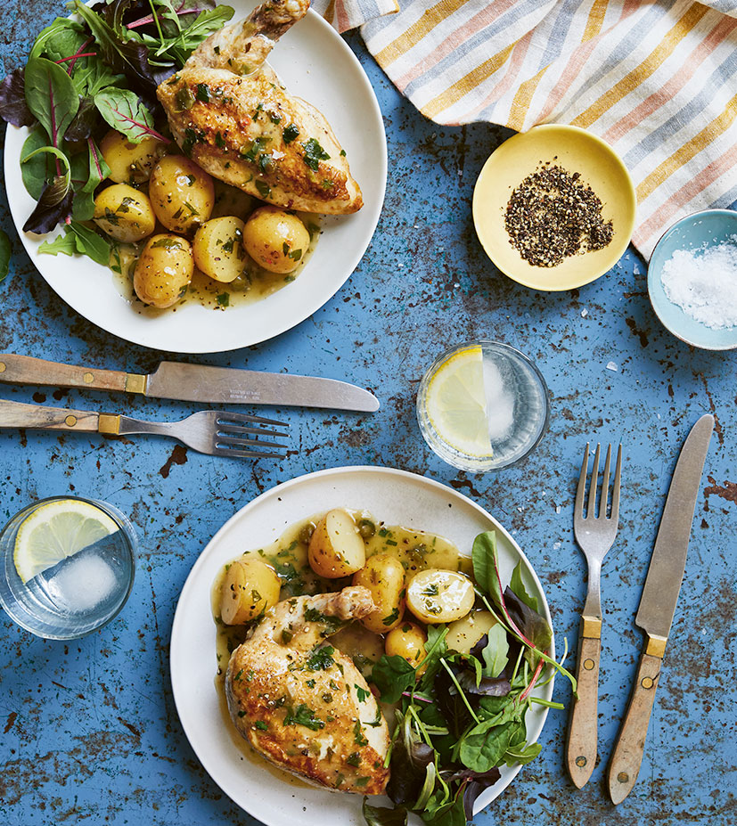 Two plates of gluten-free easy chicken picatta prepared in the slow cooker. The chicken pieces are arranged on a white plate with baby potatoes and salad leaves.