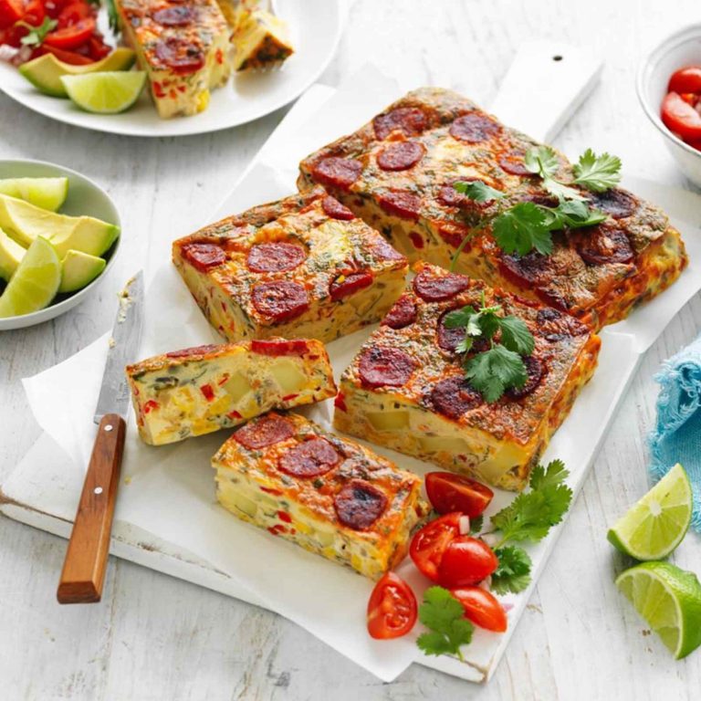 Delicious gluten-free Mexican Slice with chorizo and eggs, garnished with fresh coriander, served with lime wedges and avocado slices.